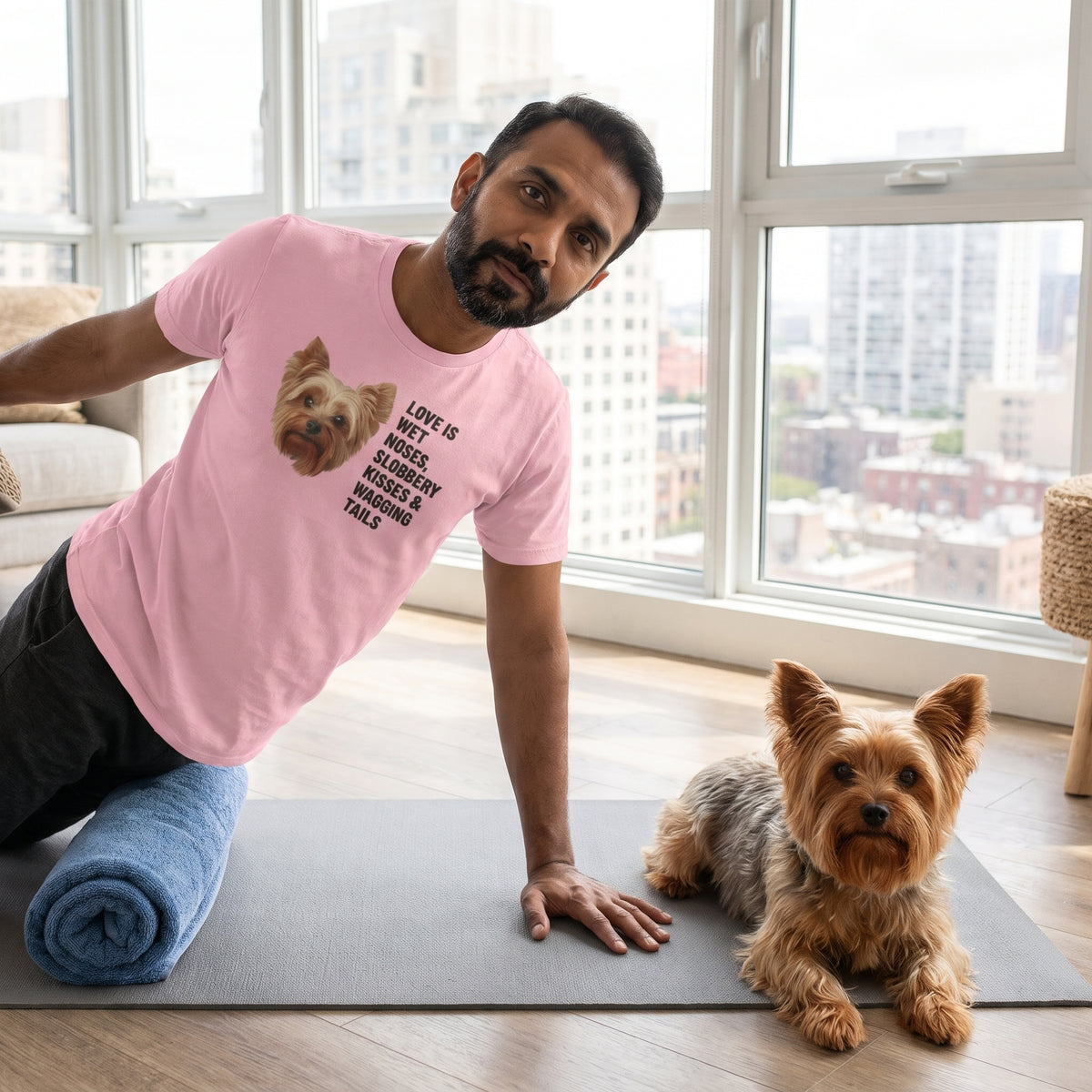 A South Asian man in his 40s with a neat beard wearing a custom pet t-shirt (Pink) printed with "Love Is Wet Noses, Slobbery Kisses & Wagging Tails" and an illustration of Gizmo the Yorkshire Terrier, with Gizmo beside them. [ks Colour=Pink; kind=lifestyle]
