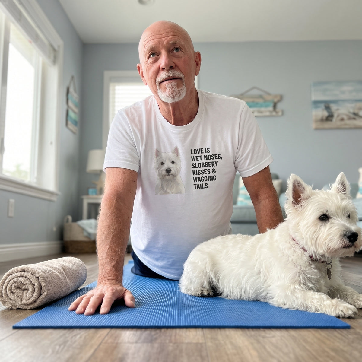 A man in his 60s, bald with a white goatee wearing a custom pet t-shirt (White) printed with "Love Is Wet Noses, Slobbery Kisses & Wagging Tails" and an illustration of Daisy the West Highland White Terrier, with Daisy beside them. [ks Colour=White; kind=lifestyle]
