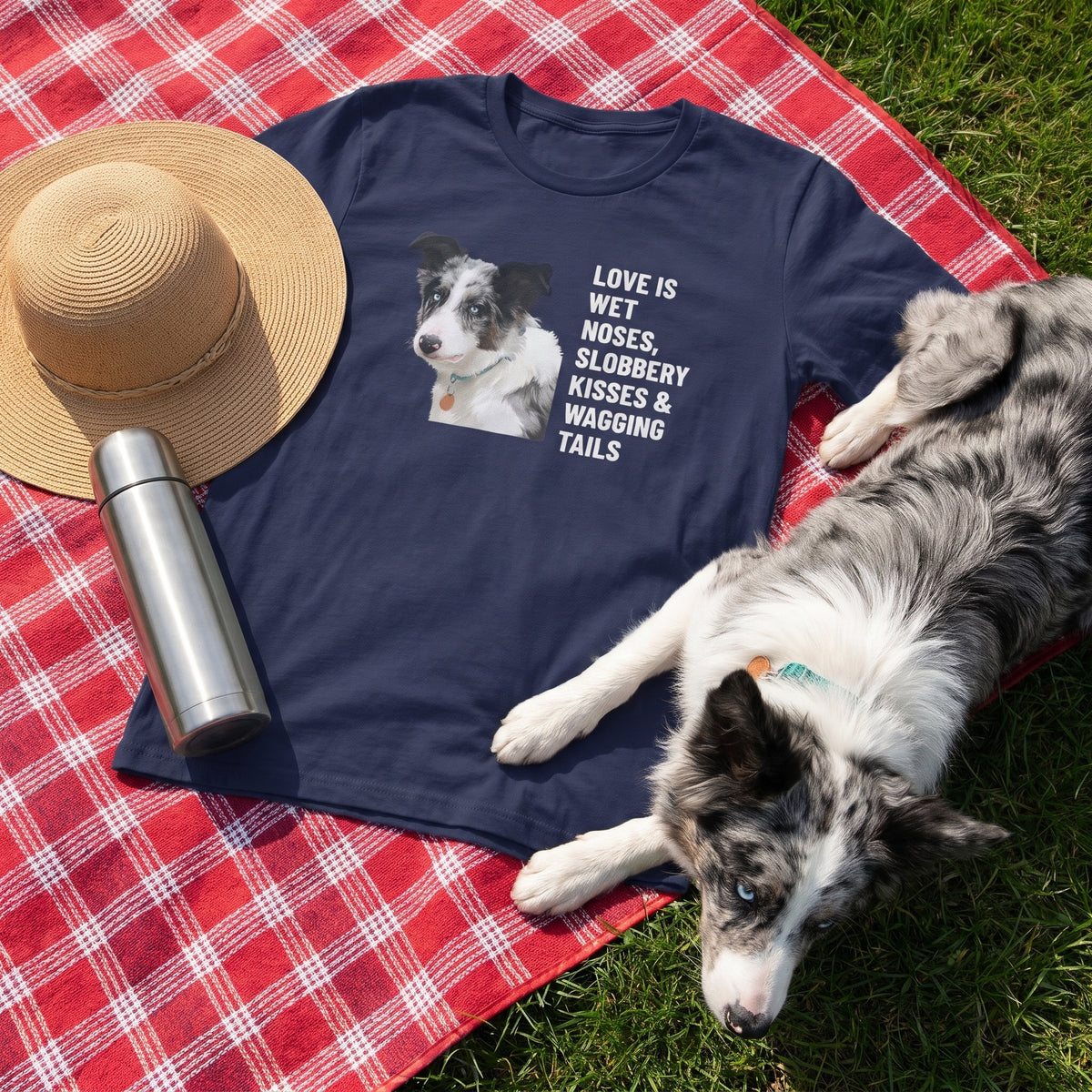 A custom pet t-shirt (Navy) printed with "Love Is Wet Noses, Slobbery Kisses & Wagging Tails" and an illustration of Willow the Border Collie, at the picnic blanket, with Willow nearby. [ks Colour=Navy; kind=lifestyle]