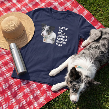 A custom pet t-shirt (Navy) printed with "Love Is Wet Noses, Slobbery Kisses & Wagging Tails" and an illustration of Willow the Border Collie, at the picnic blanket, with Willow nearby. [ks Colour=Navy; kind=lifestyle]